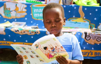 Un jeune garçon lit un livre.