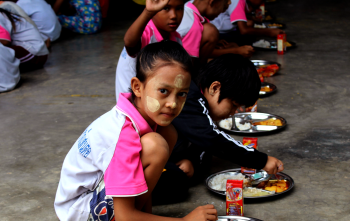 Les enfants s'assoient pour manger ensemble dans une école en Thaïlande.