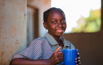 Une fille avec un mug de nourriture à l'école.