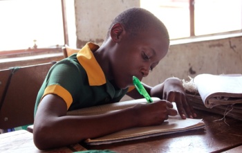 Un enfant prend des notes en classe.