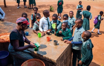 Un bénévole cuisinier sert de la nourriture aux enfants à l'école.