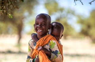 Un jeune garçon au Turkana, au Kenya, porte son frère ou sa sœur.