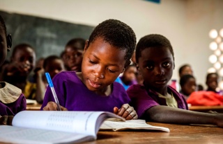 Un jeune garçon prend des notes en classe dans une école au Malawi.