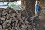 Mary's Meals member of staff stands next to a collapsed wall.