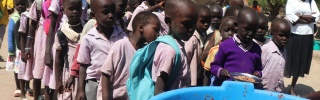 Les enfants au Soudan du Sud font la queue pour recevoir de la nourriture à l'école.