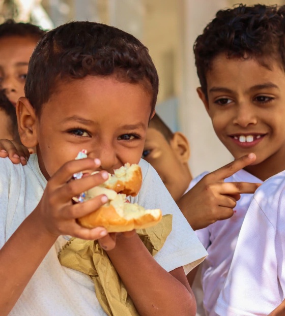 Les enfants mangent ensemble dans une cour d'école.